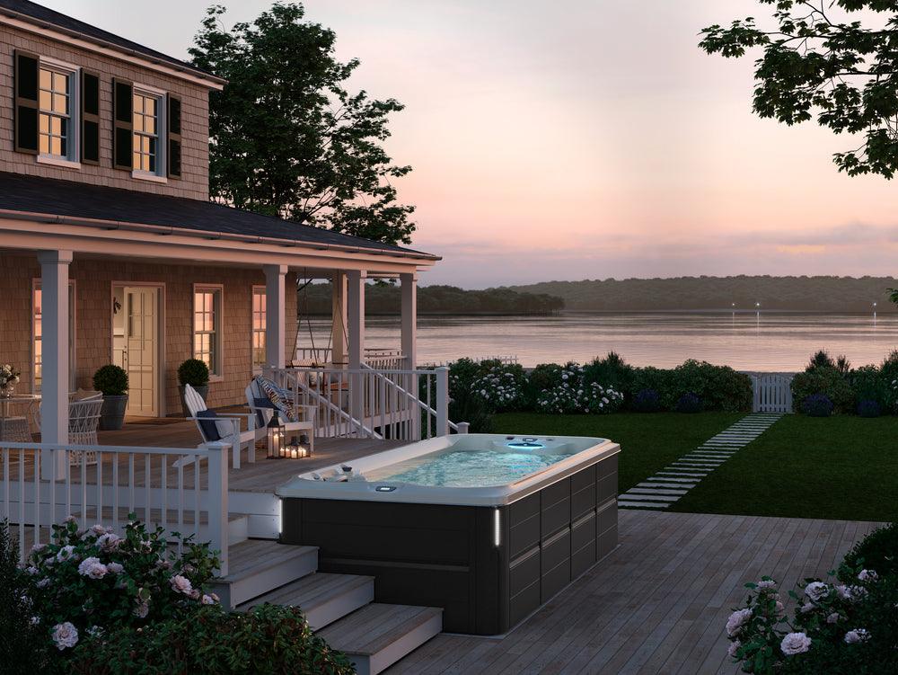 Jacuzzi® PowerPro™ Swim Spa on a wooden deck overlooking water, available at Jacuzzi Hot Tubs Rochester, NY.