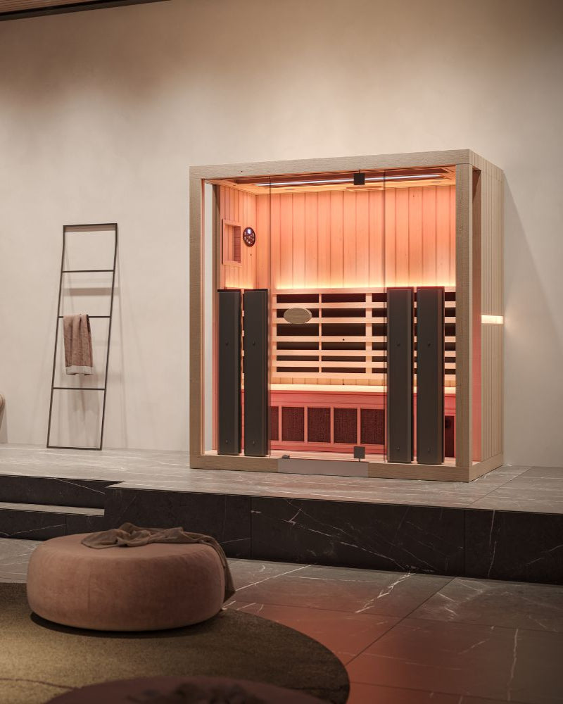 Infrared sauna in a modern room with a towel rack and ottoman.