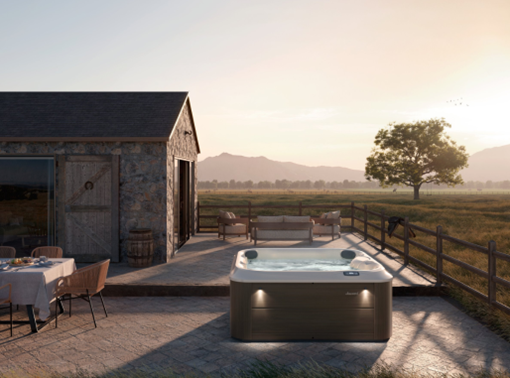 Outdoor hot tub on a patio with a scenic view of a barn and open field.